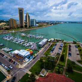 Paradise Gulf of Mexico Corpus Christi Texas Marina Aerial. The T-head with the marina , boats , sailboats , yachts , Tall Twin Towers at downtown Corpus Christi. Calm waters on the pier and inside the marina or harbor. The USS lexington is in the distance also called the " Blue Ghost "